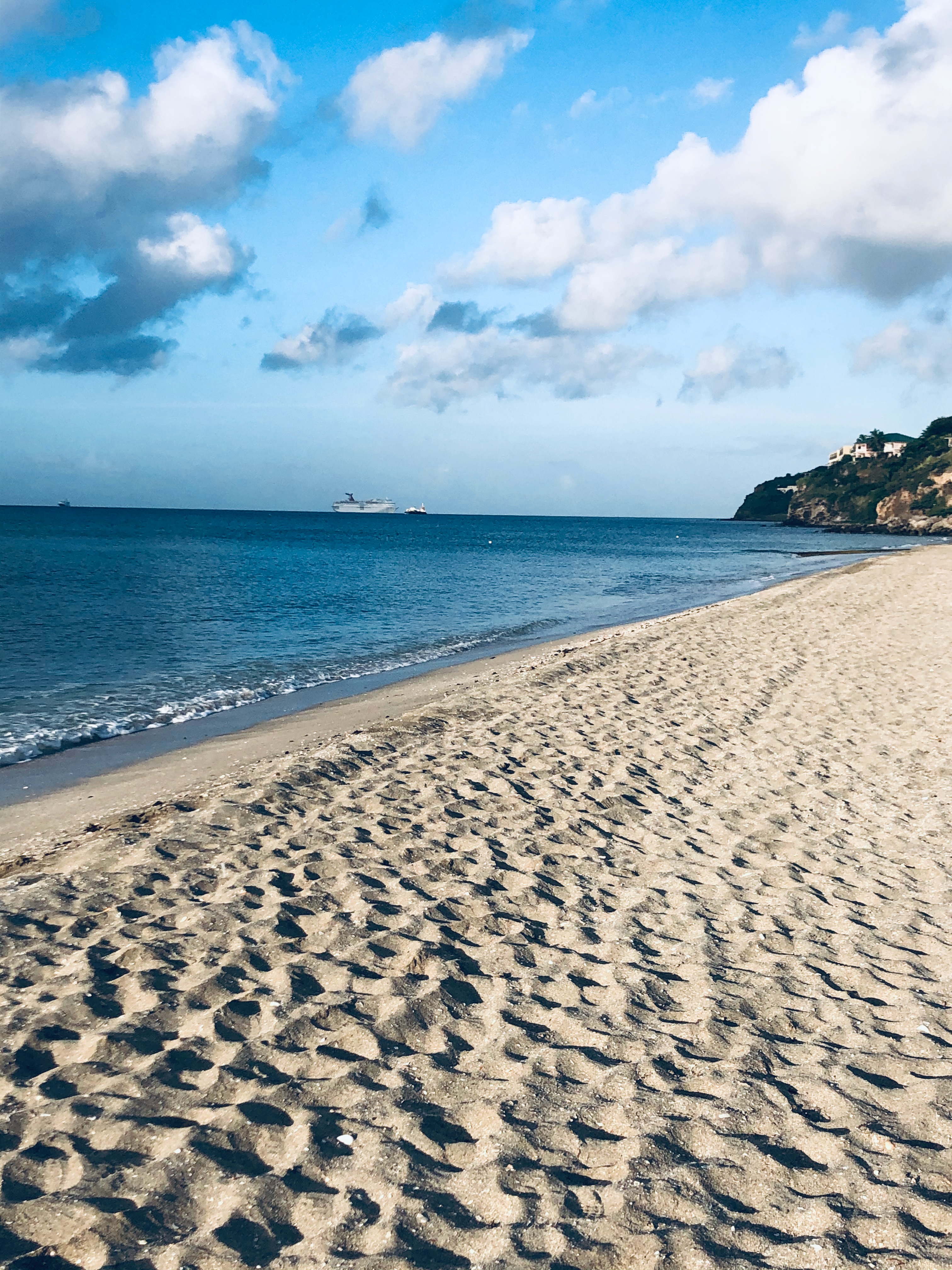 Pristine sandy beach with crystal-clear water and cruise ship in the distance
